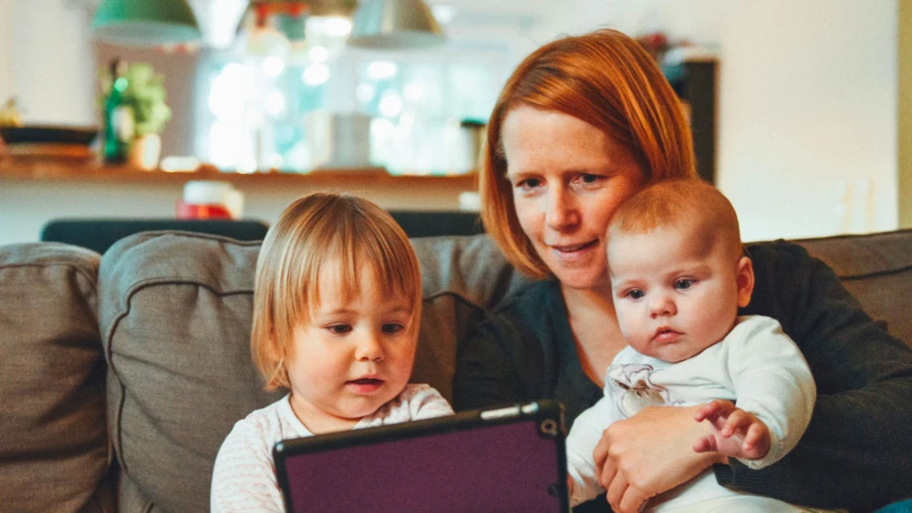 Parent with two young children using a tablet at home