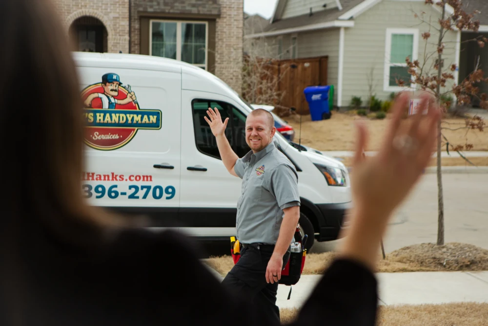 Hank's technician waving beside a branded van at a customer home