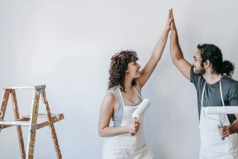 Couple celebrating while painting an interior wall together