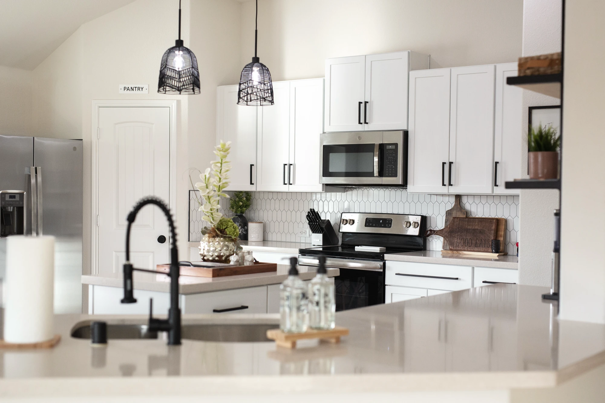 Black kitchen faucet and white island in a completed remodel