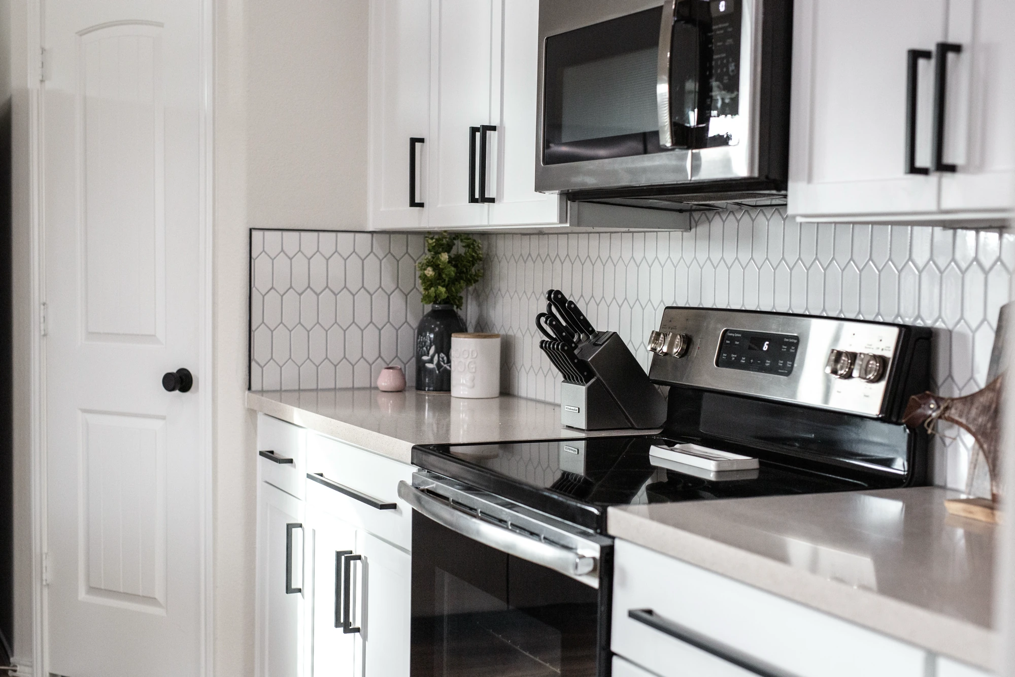 Close view of white cabinets, black hardware, and stainless appliances