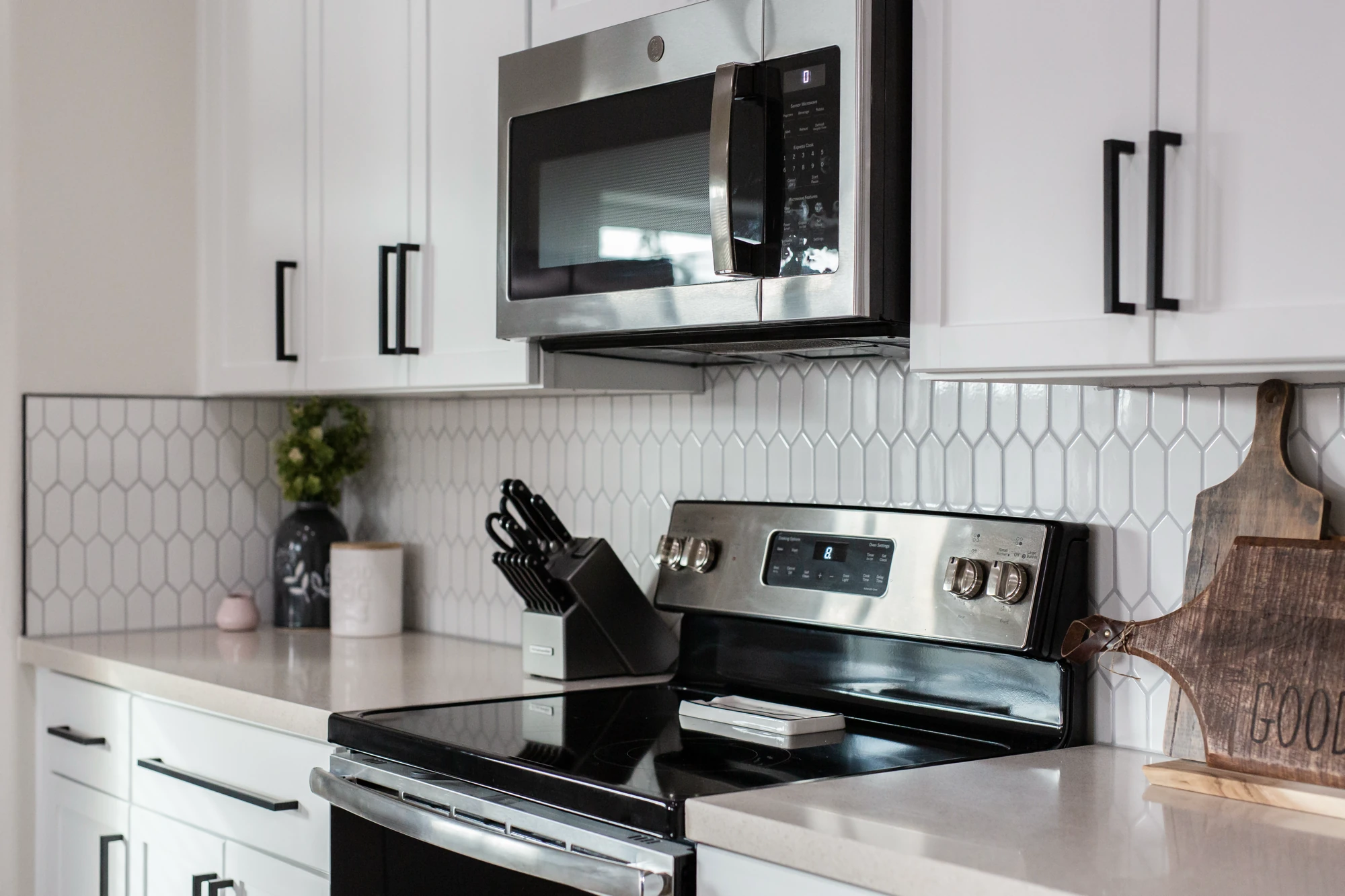 Stainless range and microwave above a geometric tile backsplash