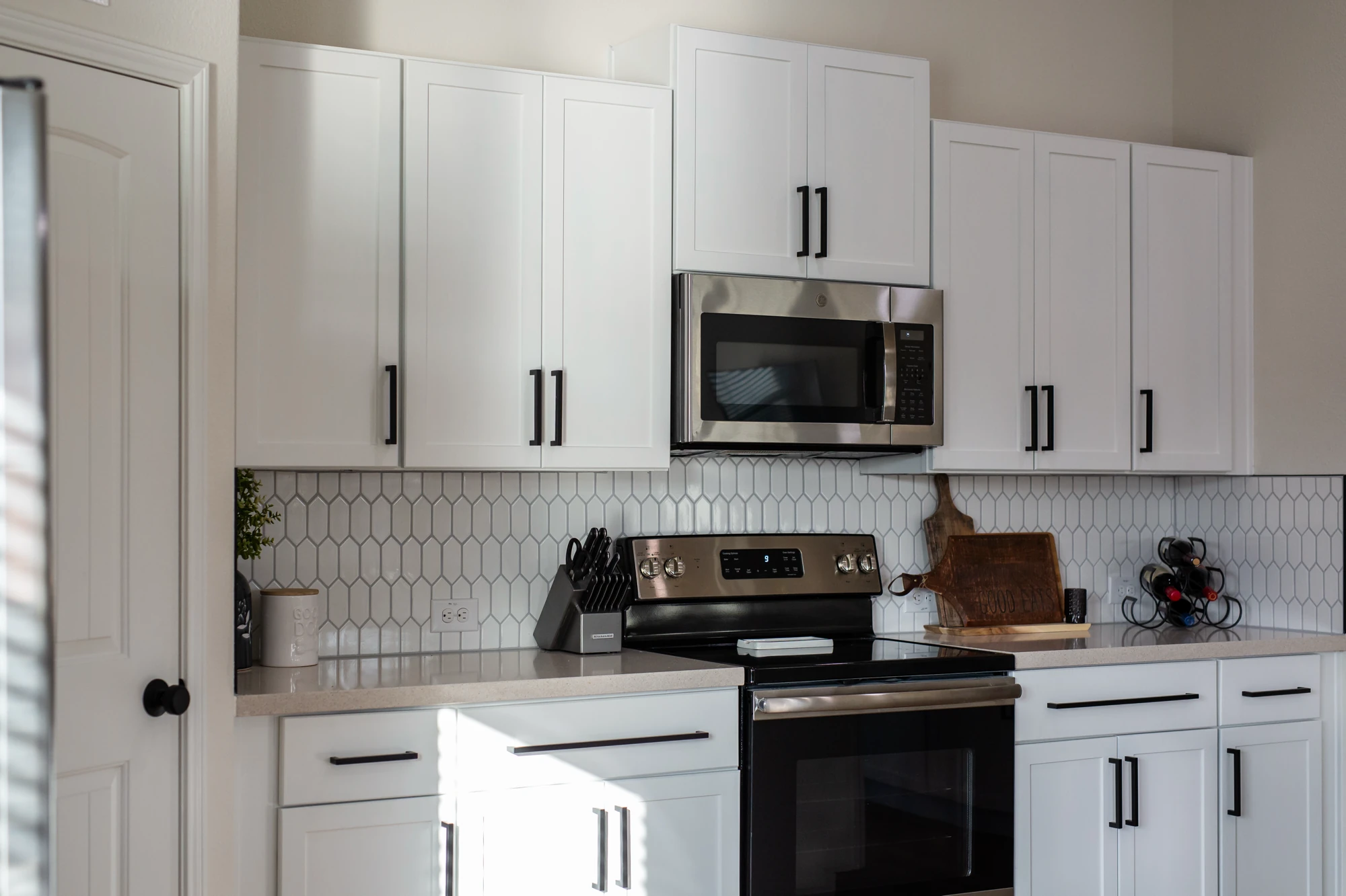 White kitchen cabinets framing a stainless range and microwave
