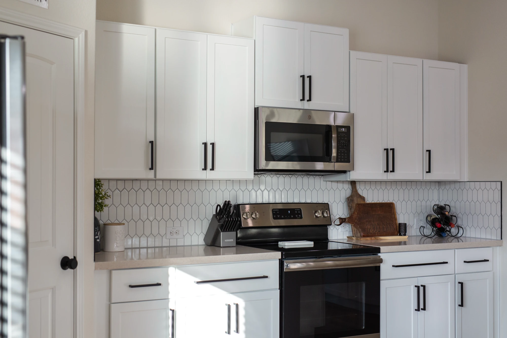 Completed white kitchen with black hardware and stainless appliances