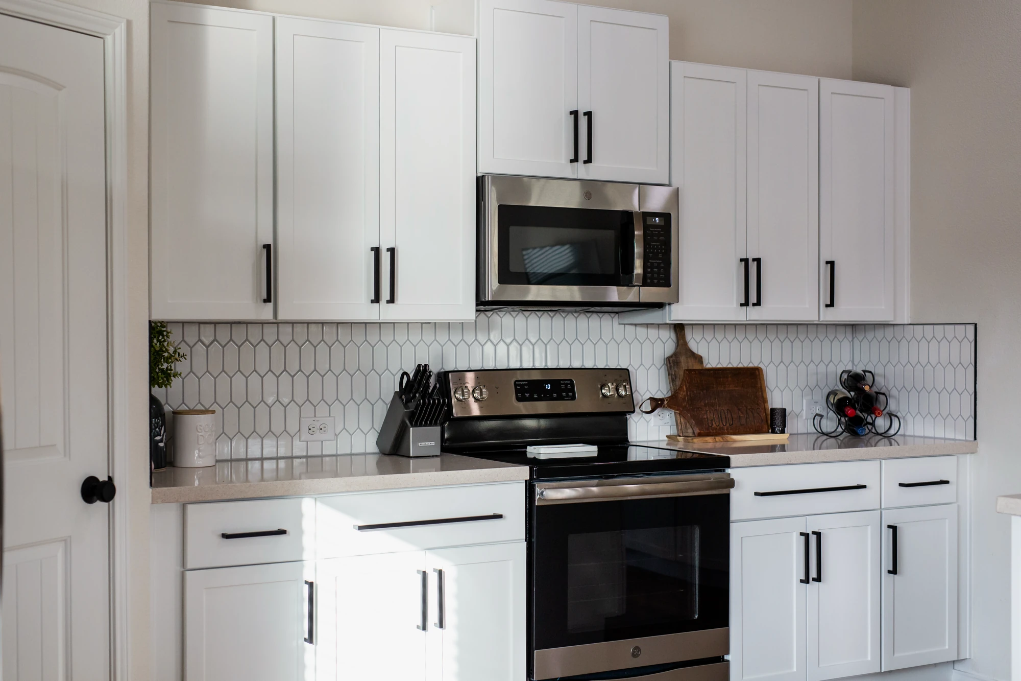 Stainless range centered between new white kitchen cabinets