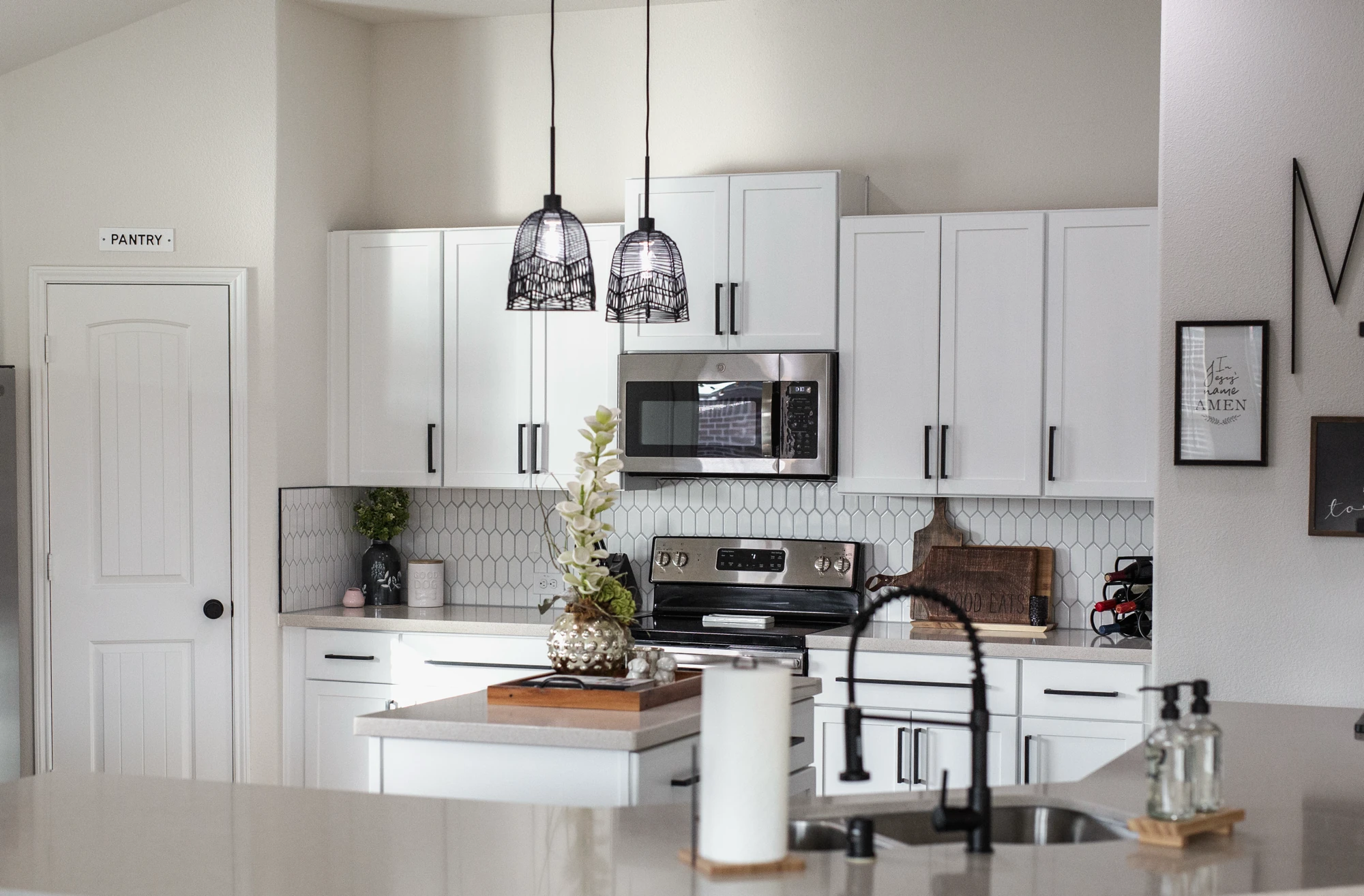 Remodeled white kitchen viewed across the sink and island