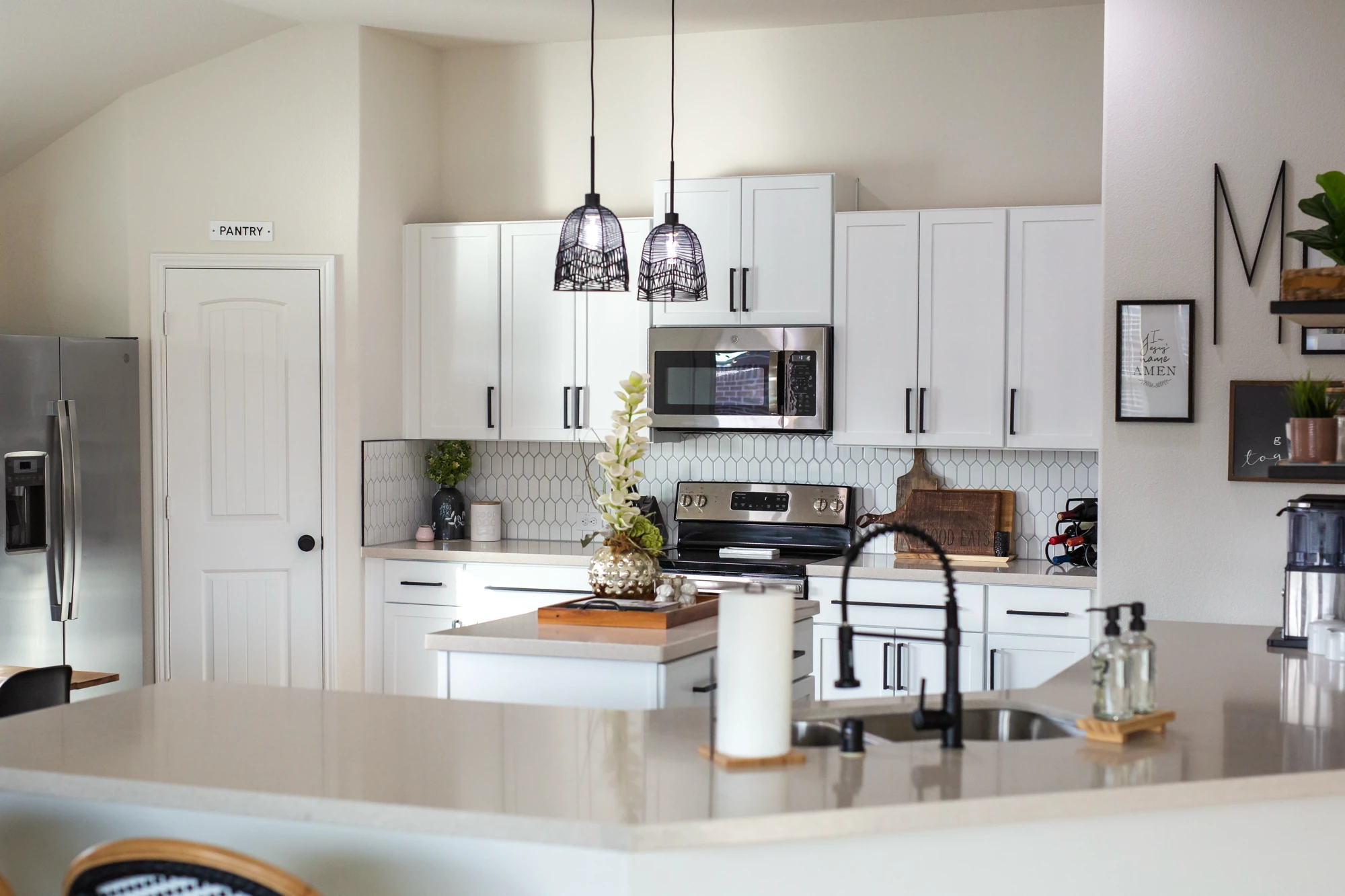 White kitchen island beneath dark pendant lights