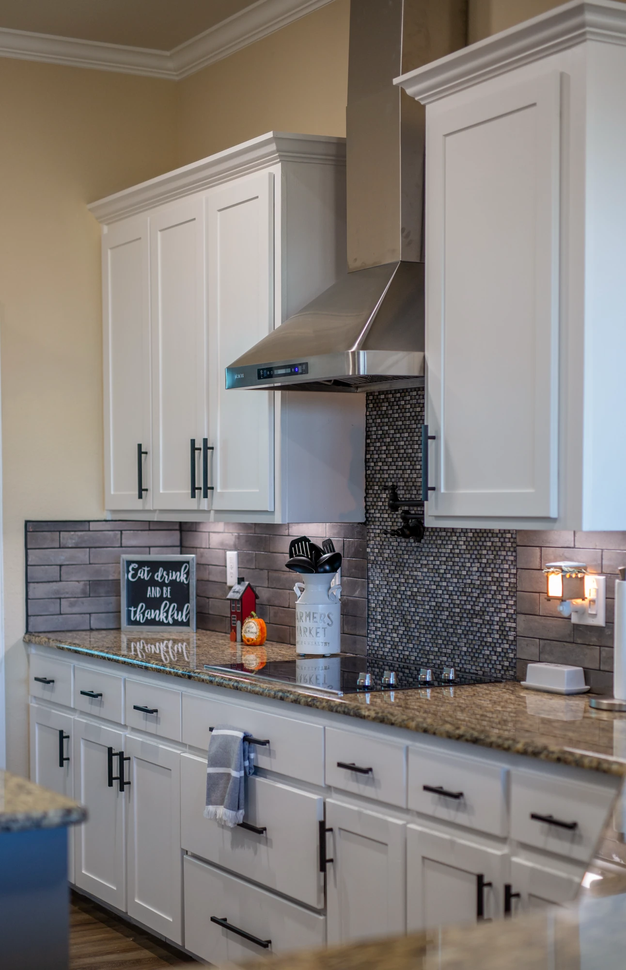 Remodeled kitchen with white cabinets and a dark tile backsplash
