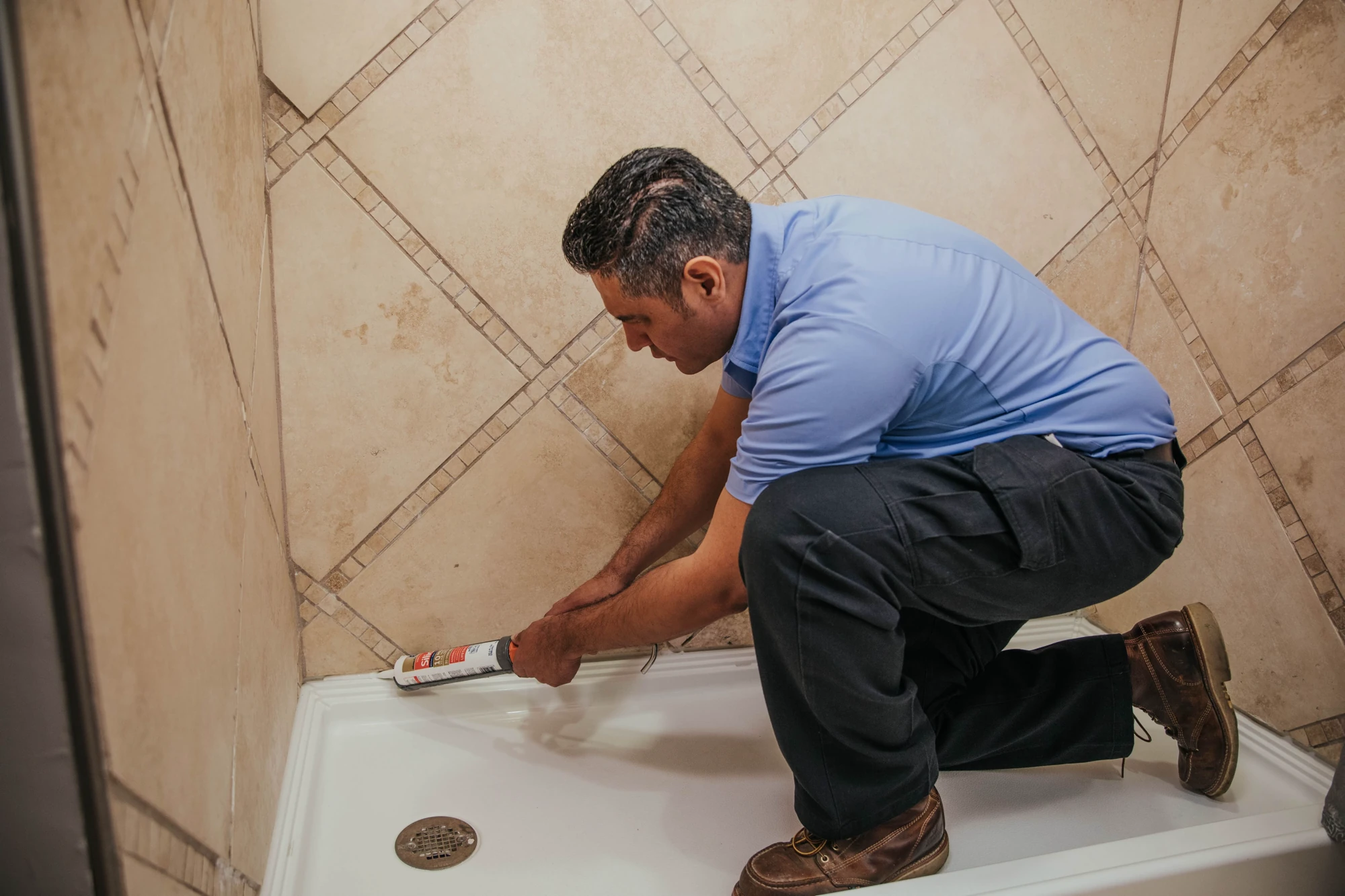 9A0A8929 Hank's technician applying caulk around a tiled bathtub