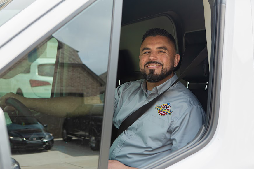 Hank's technician seated inside a branded service van