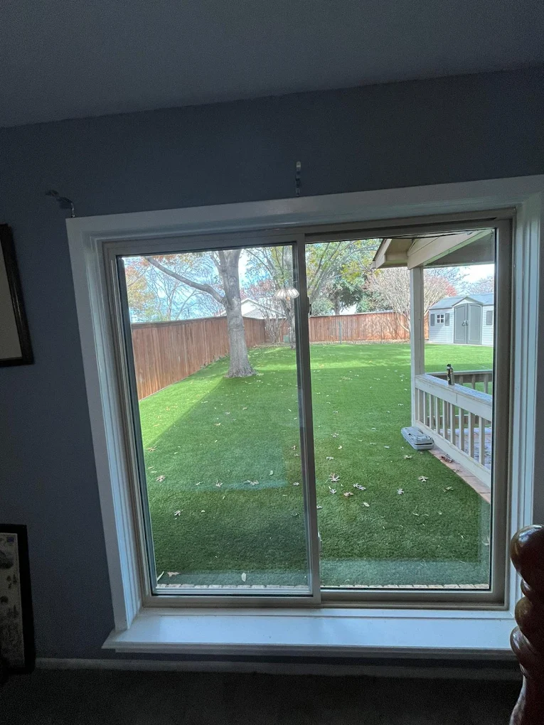 Wide interior window overlooking a green backyard