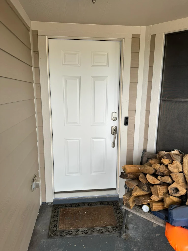 White entry door beside neatly stacked firewood