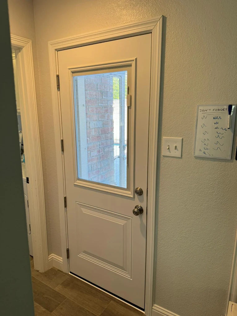 White exterior door with a full glass panel viewed from indoors