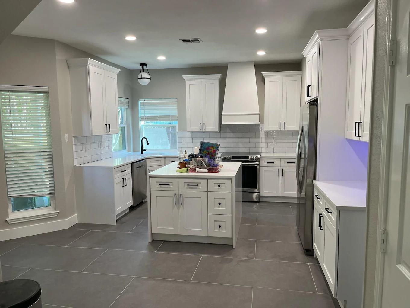 Spacious white kitchen with a center island and gray tile floor